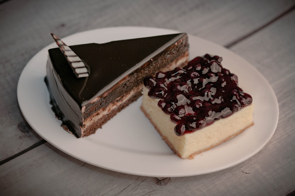 Chocolate layer cake beside a blueberry cheesecake