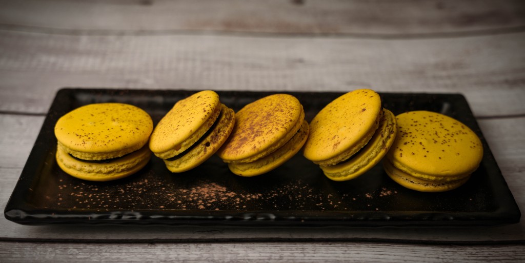 Yellow macarons on a black plate